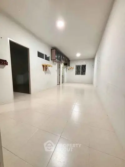 Spacious empty room with tiled flooring and bright lighting, ideal for customization.