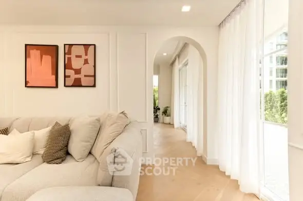Elegant living room with plush sofa and modern art, featuring bright natural light and stylish decor.