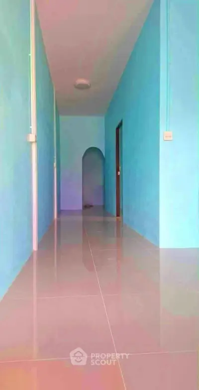 Spacious hallway with glossy tiled floor and vibrant blue walls