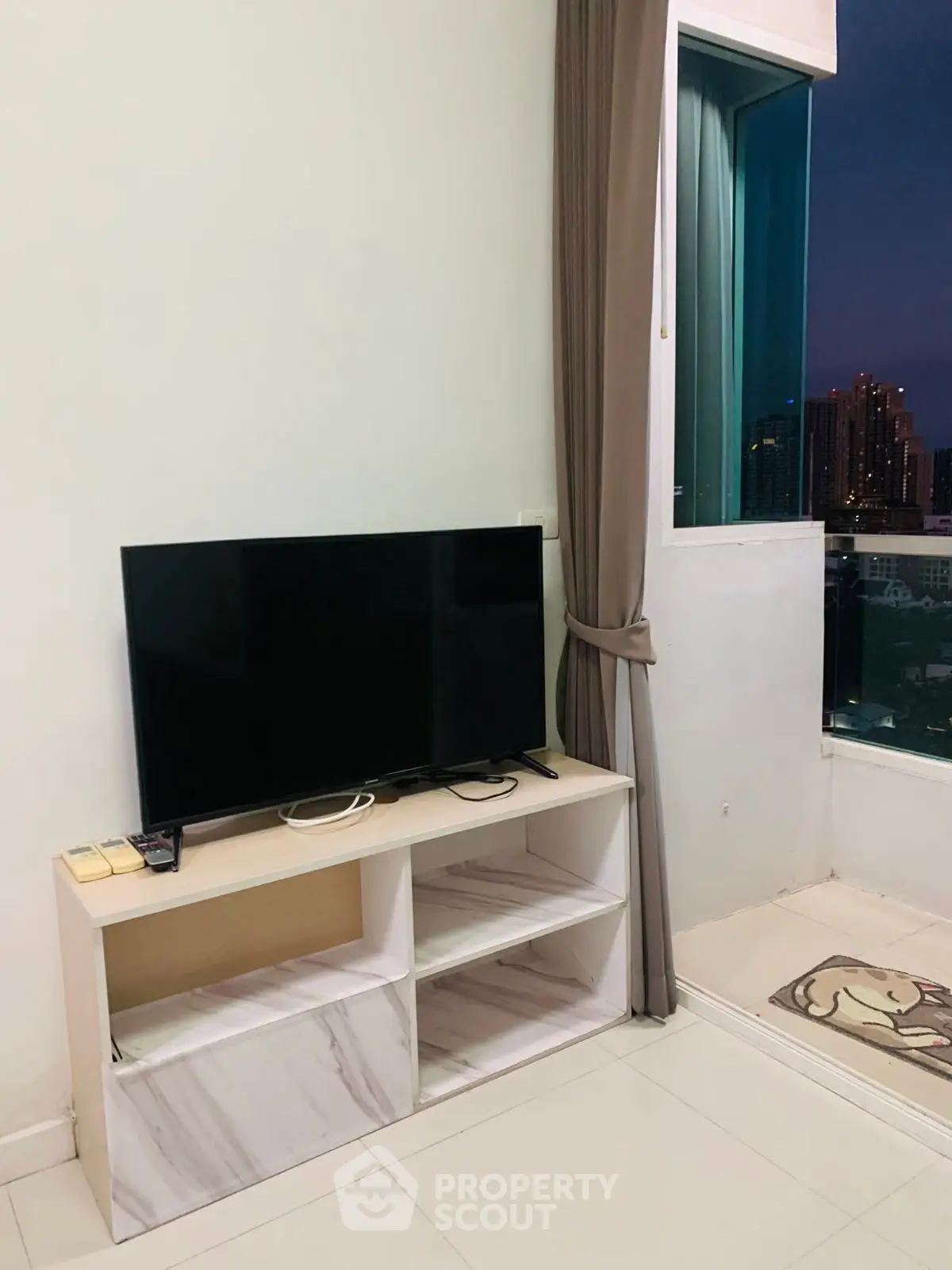 Modern living room with TV stand and city view from window, ideal for urban living.