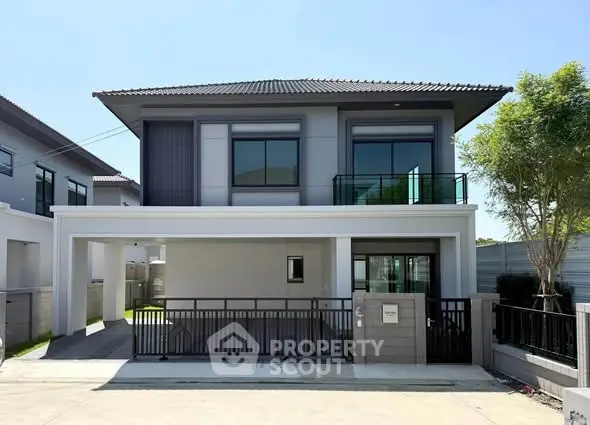 Modern two-story house with sleek design and spacious driveway in a suburban neighborhood.