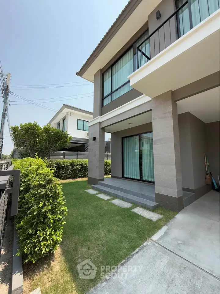 Modern two-story house with landscaped garden and large windows in a serene neighborhood.