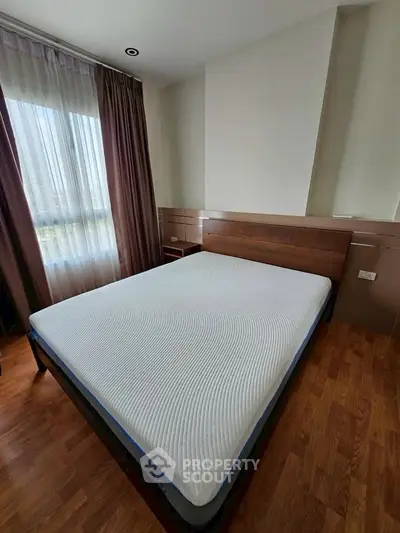 Spacious bedroom with large window and modern wooden flooring