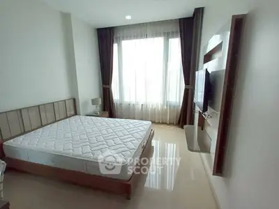 Bright bedroom with large window and wall-mounted TV in modern apartment.