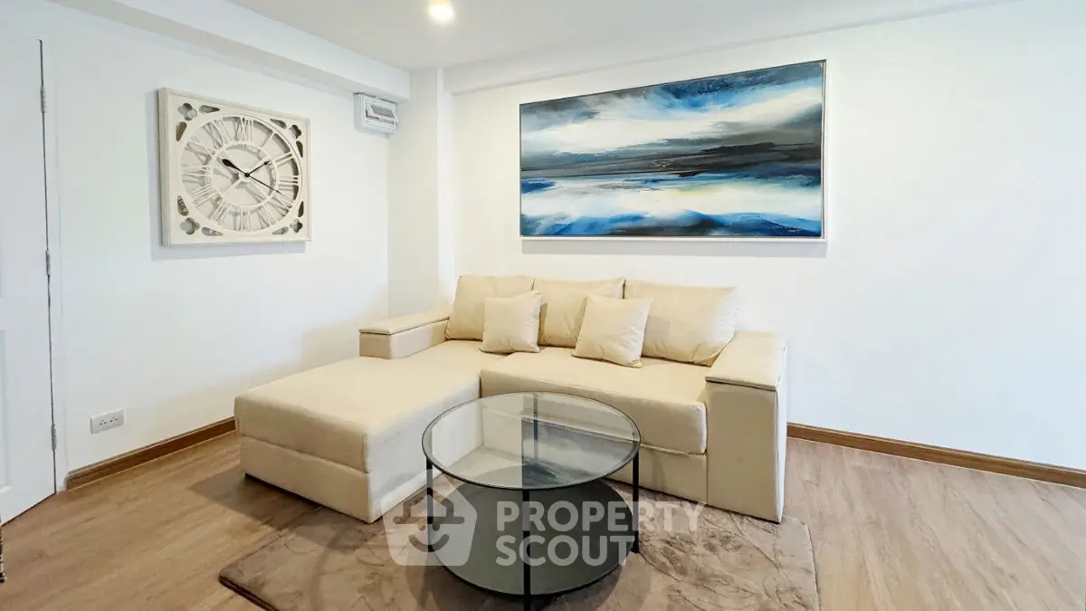Modern living room with stylish beige sofa and abstract art on wall.