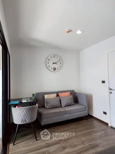 Cozy living room with modern sofa and wall clock, perfect for relaxation.