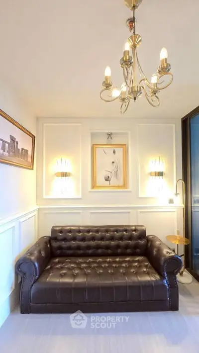 Elegant living room with leather sofa, chandelier, and stylish wall art.