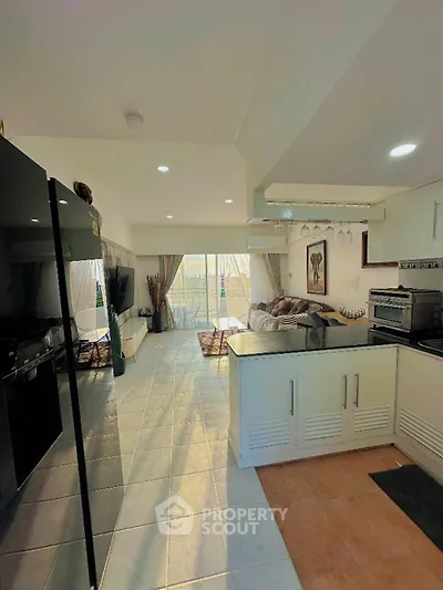 Spacious open-layout living room with modern kitchen and large windows for natural light.