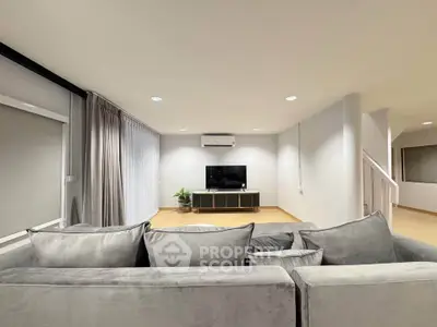 Spacious modern living room with sleek grey sofa and wall-mounted TV, perfect for relaxation.