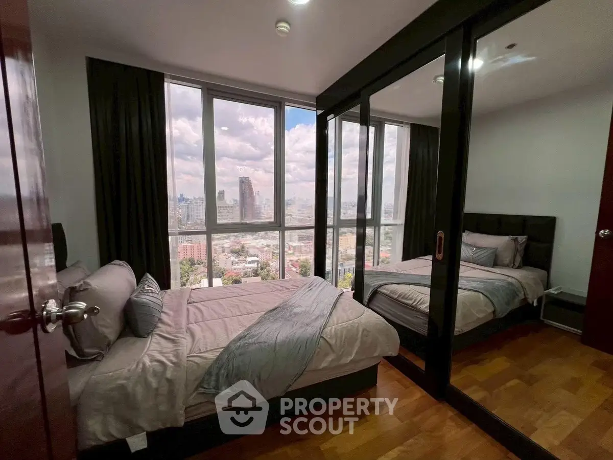 Luxurious bedroom with stunning city view and mirrored wardrobe in high-rise apartment.