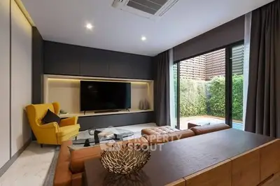 Modern living room with stylish furniture and large TV, featuring a cozy ambiance and garden view.