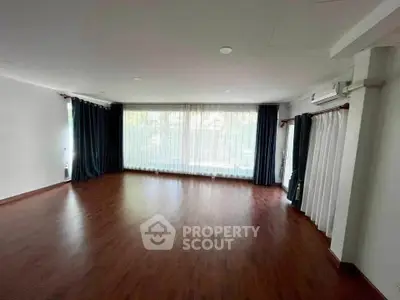 Spacious living room with large windows and elegant curtains, perfect for natural light and modern living.