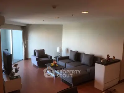 Spacious modern living room with stylish gray furniture and wooden flooring, perfect for relaxation.