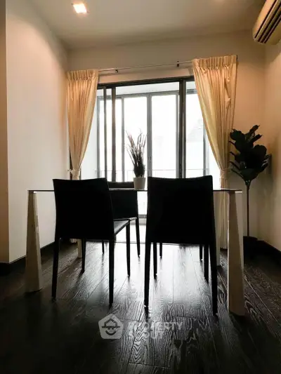 Elegant dining area with glass table and chairs, featuring floor-to-ceiling windows and stylish curtains.