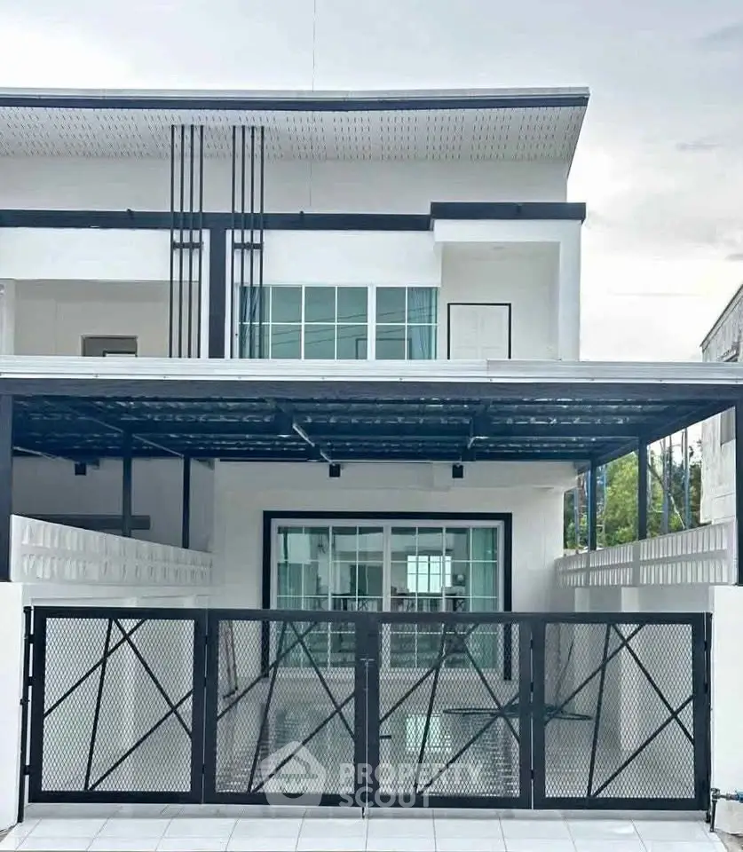 Modern two-story house with sleek black and white exterior and spacious driveway.