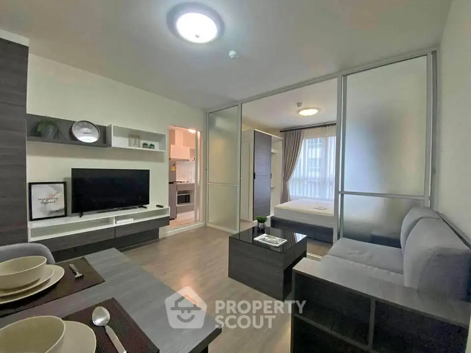 Modern open-plan living room with kitchen and bedroom in sleek apartment.