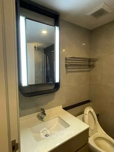 Modern bathroom with sleek vanity and illuminated mirror in contemporary apartment.