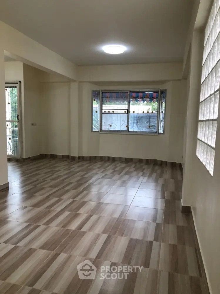 Spacious living room with large window and modern tiled flooring