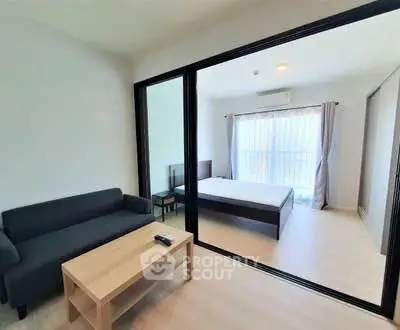 Modern open-plan living room with sliding glass doors leading to a bright bedroom.