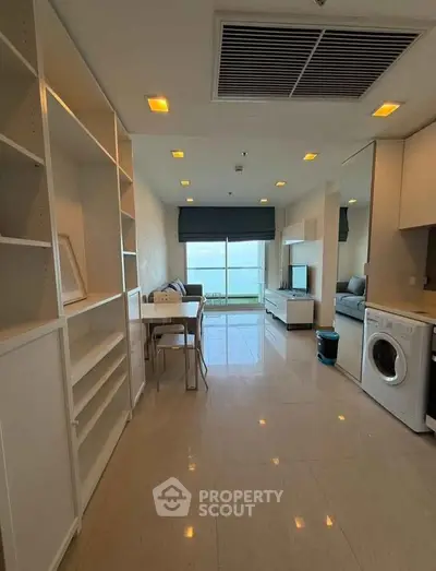 Modern living room with sleek furniture and built-in washing machine, bright and spacious.