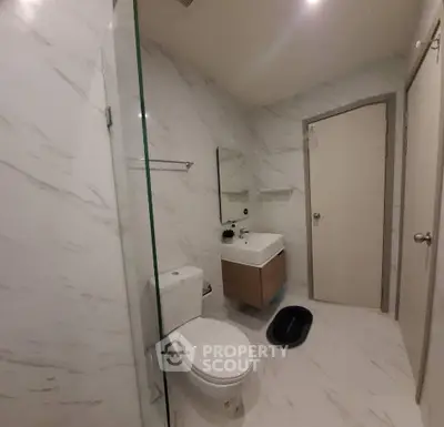 Modern bathroom with sleek design and marble walls, featuring a glass shower and contemporary fixtures.
