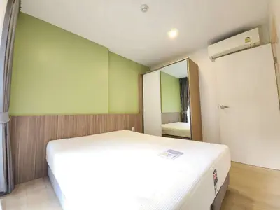 Modern bedroom with green accent wall and mirrored wardrobe