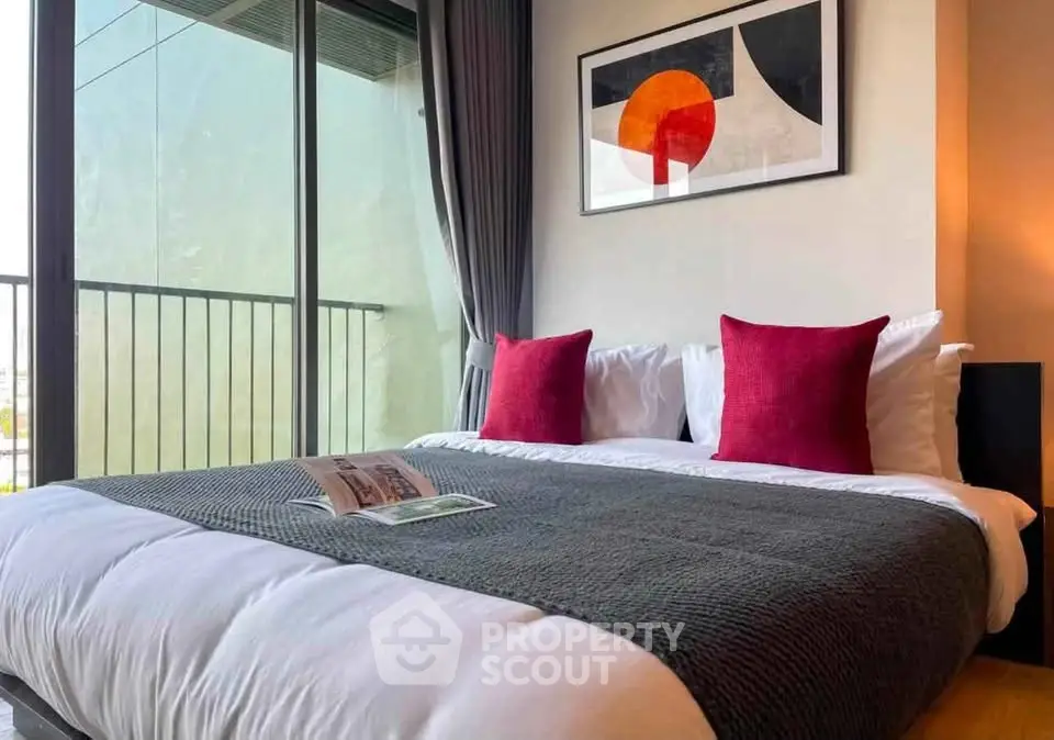 Modern bedroom with stylish decor and balcony view, featuring cozy bedding and contemporary artwork.