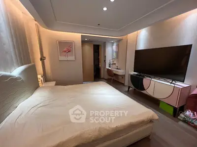 Modern bedroom with stylish decor and large TV, featuring elegant lighting and cozy ambiance.
