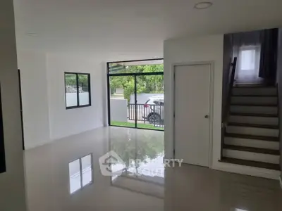 Spacious modern living room with large windows and staircase, ideal for natural light.