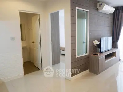 Modern living room with sleek TV unit and air conditioning, adjacent to bedroom and bathroom.