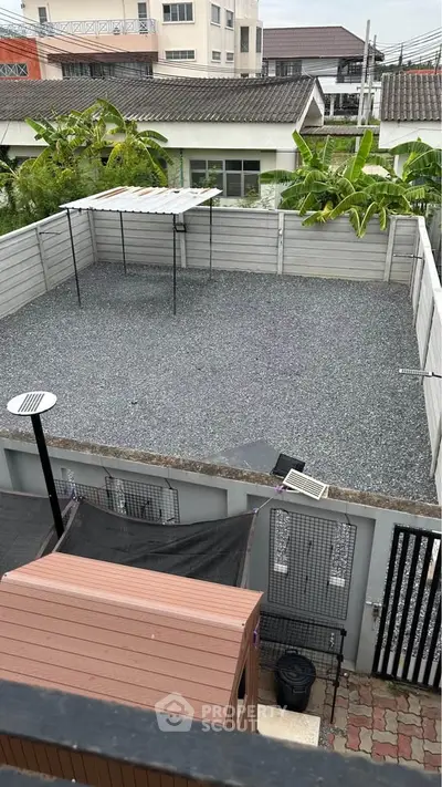 Spacious outdoor area with gravel surface and covered section, ideal for versatile use.