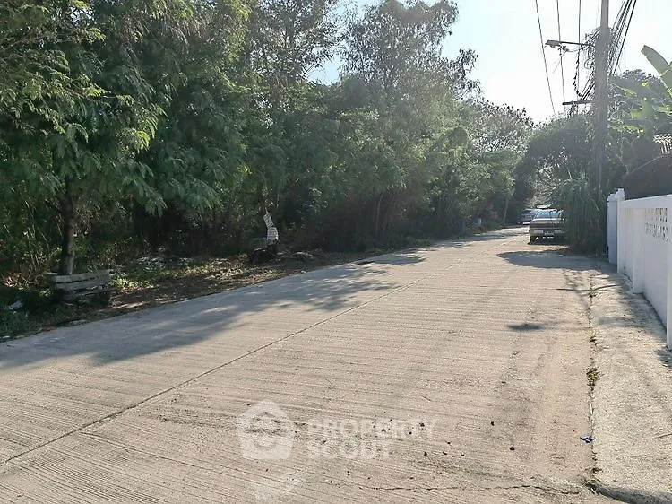 Quiet residential street with lush greenery and parked car, ideal for peaceful living.