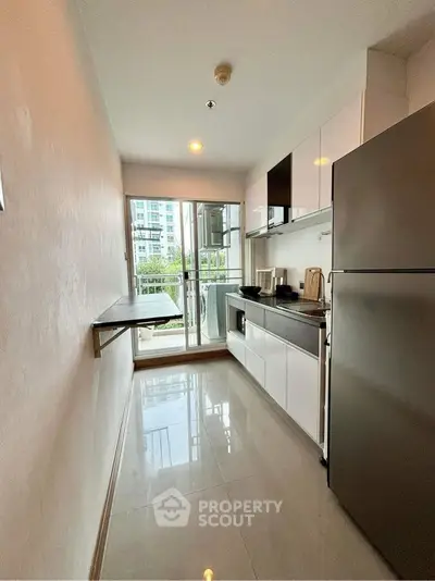 Modern kitchen with sleek appliances and balcony view in urban apartment.