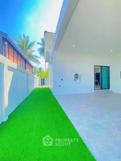 Modern home exterior with lush green lawn and spacious patio area.