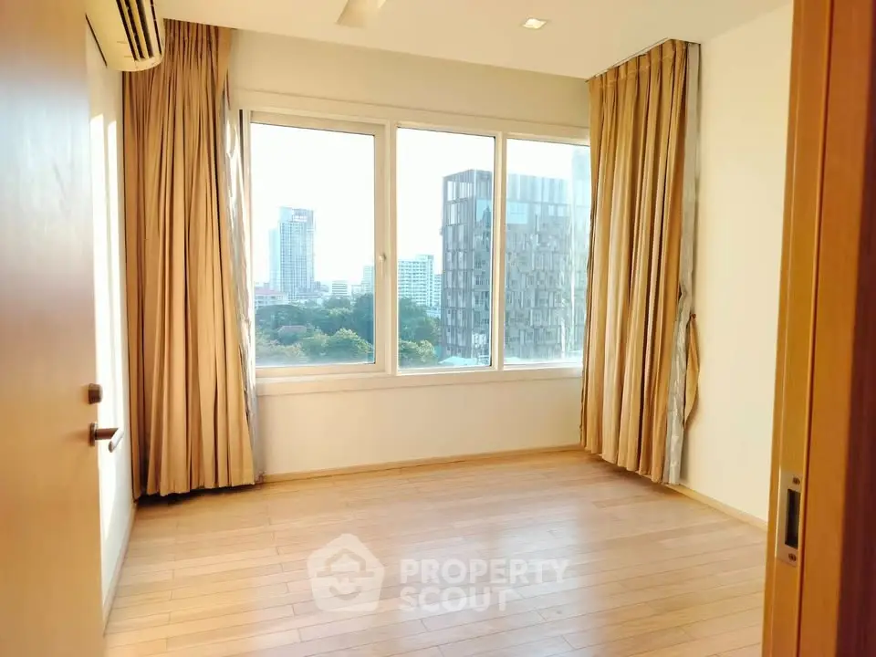 Spacious room with large windows offering a stunning city view, perfect for a modern urban lifestyle.