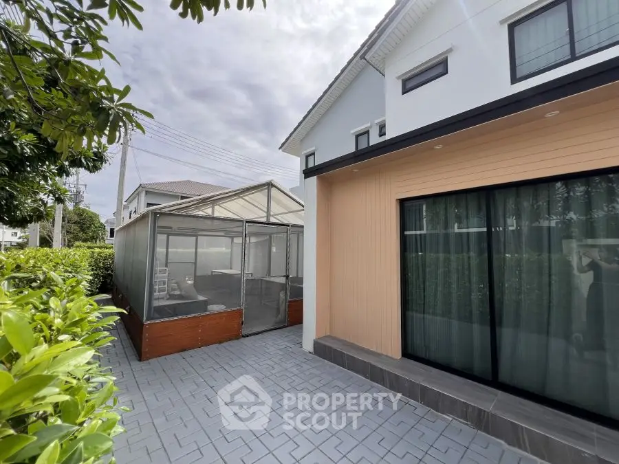 Modern house exterior with glass greenhouse and spacious patio