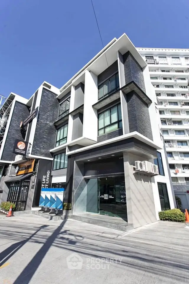 Modern urban building with sleek design and large windows in a vibrant city setting.