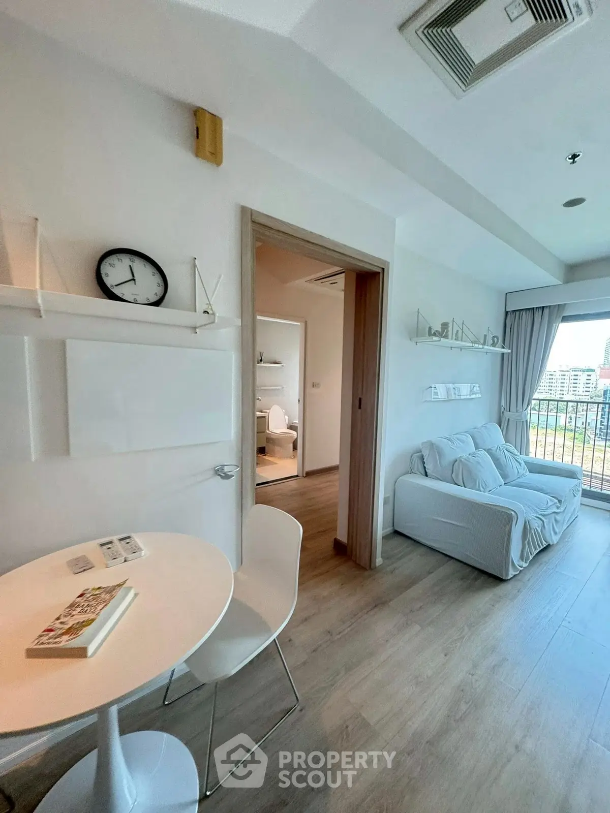 Modern living room with cozy seating and balcony view in a stylish apartment.