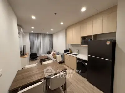 Modern open-plan living room and kitchen with sleek appliances and cozy seating area.