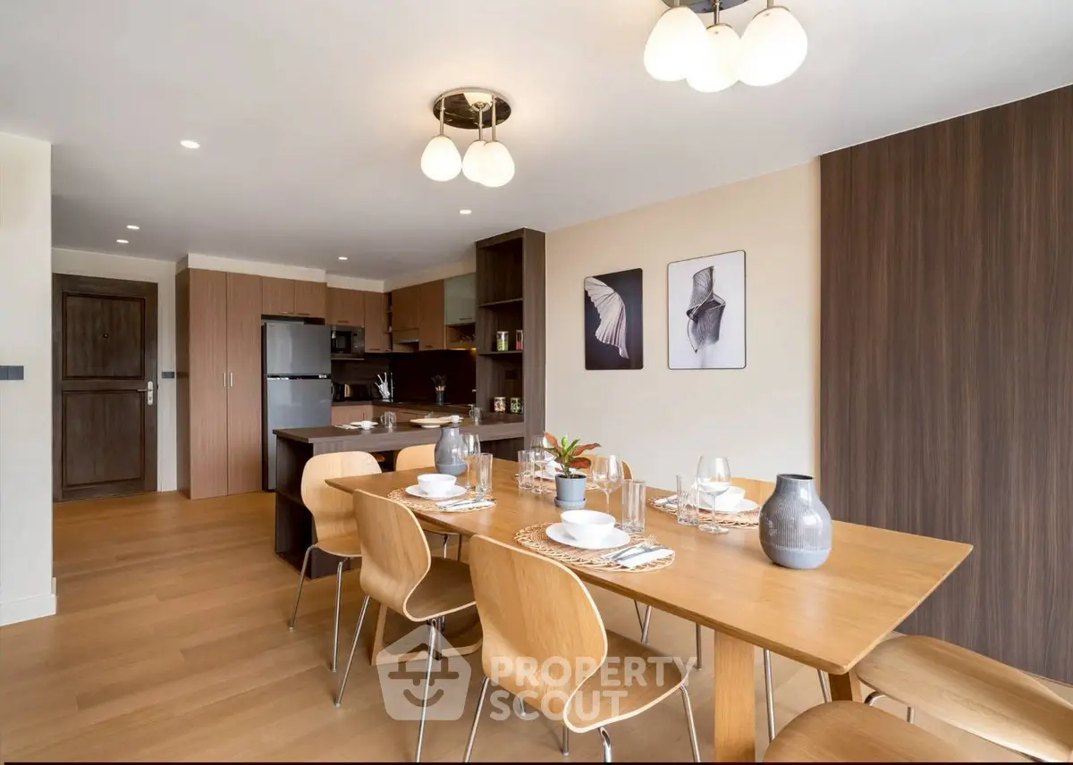 Modern dining area with wooden table and chairs, open kitchen layout, and stylish decor.