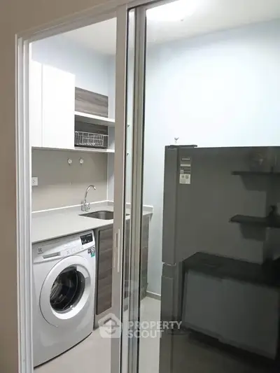 Modern kitchen with washing machine and fridge in compact layout