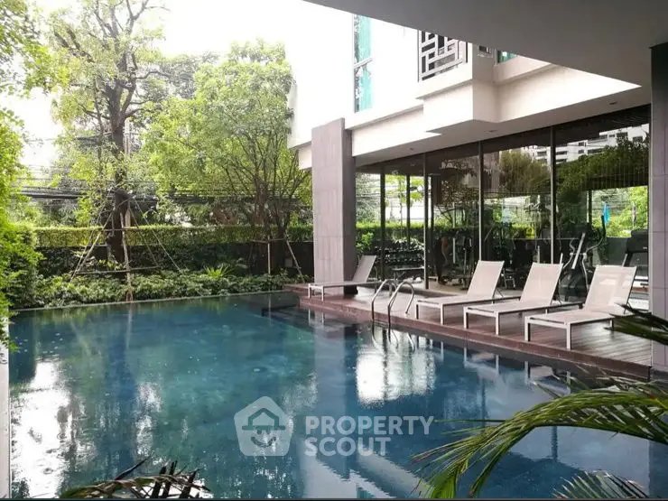 Luxurious modern poolside area with sun loungers and lush greenery