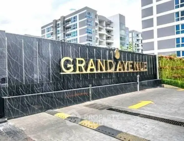 Modern apartment building entrance with Grand Avenue sign, showcasing contemporary architecture.