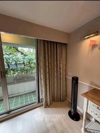 Cozy room with balcony access and greenery view, featuring elegant curtains and a stylish floor lamp.