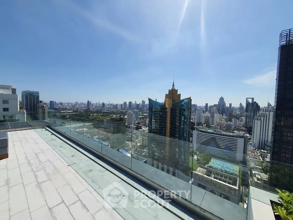 Stunning cityscape view from a modern rooftop terrace with glass railing.