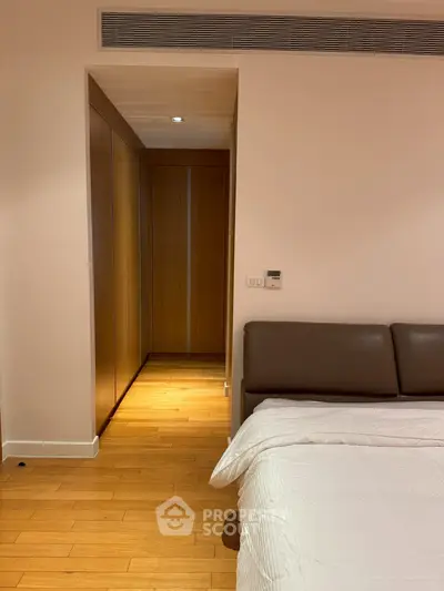 Spacious bedroom with wooden flooring and modern design, featuring a cozy bed and built-in wardrobe.