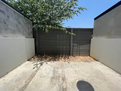 Spacious outdoor parking area with privacy walls and tree shade, ideal for secure vehicle storage.