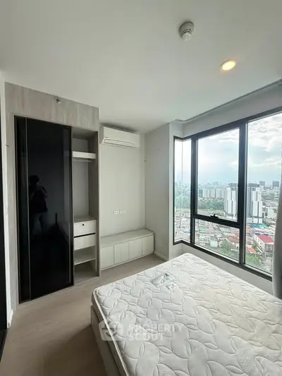 Modern bedroom with large windows offering stunning city views, featuring a built-in wardrobe and air conditioning.