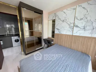 Modern bedroom with stylish marble accents and compact kitchen area featuring a washing machine.