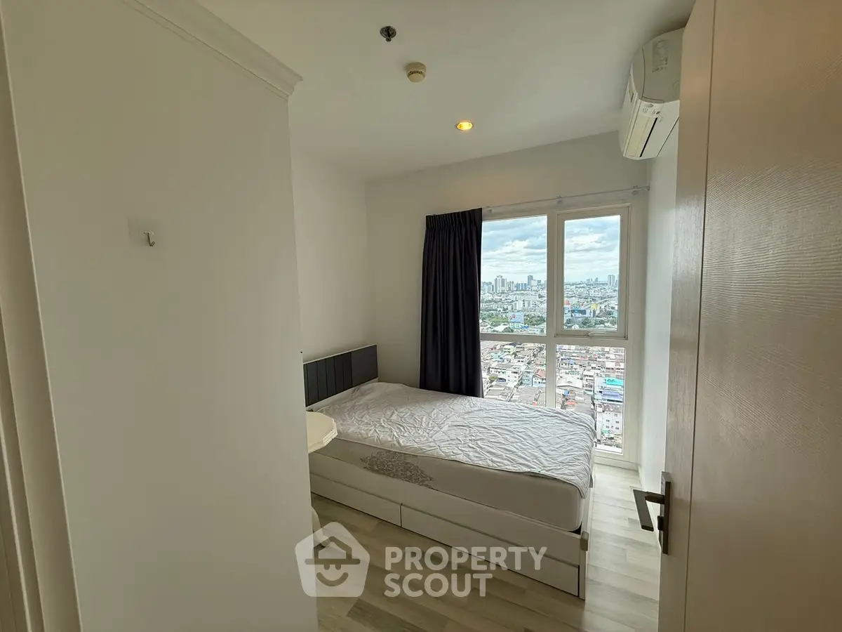 Modern bedroom with city view, featuring a cozy bed and large window for natural light.